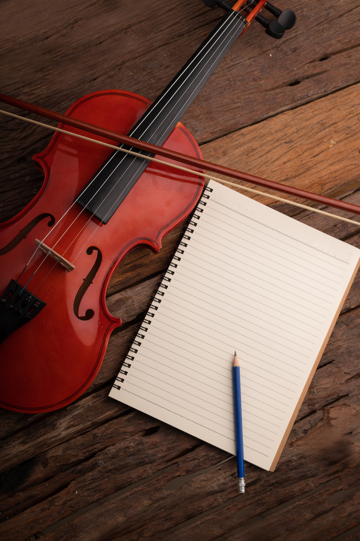 Close-up shot violin orchestra instrumental and notebook over wooden background select focus shallow depth of field